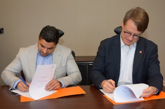 Maaz Sheikh (left) signs the deal. Maaz Sheikh (left) signs the deal.
